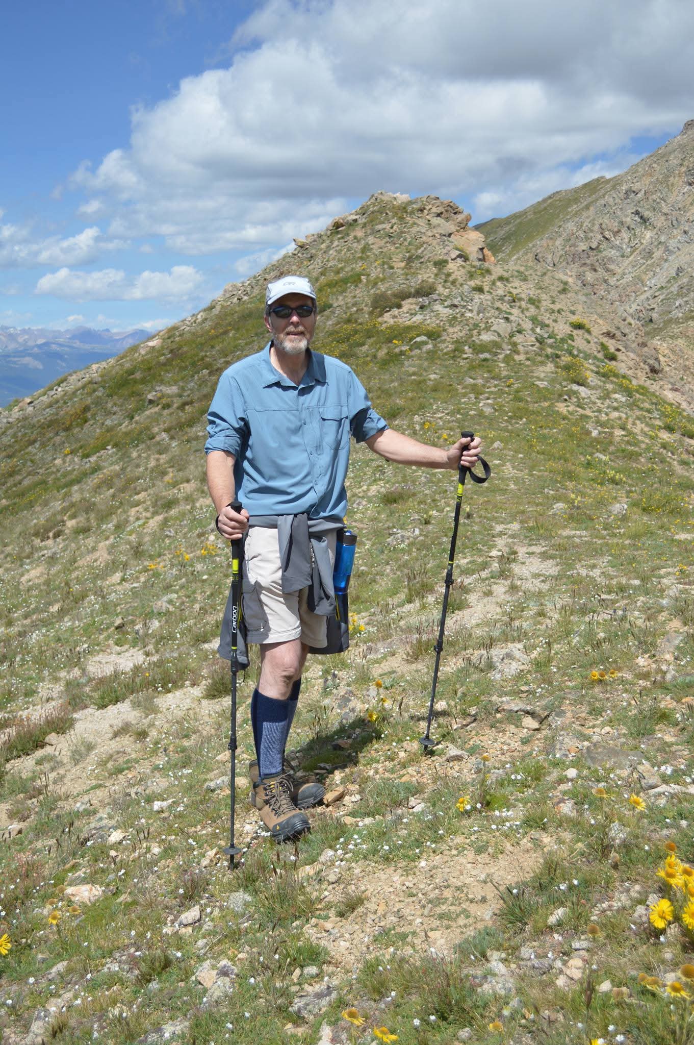 Senior hiker standing triumphantly on a mountain trail during a golden hour expedition