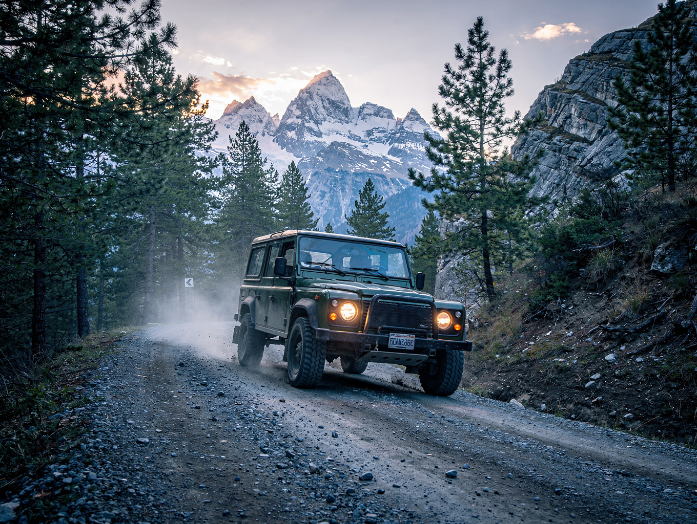 A rugged 4x4 vehicle navigating a high mountain pass at sunset